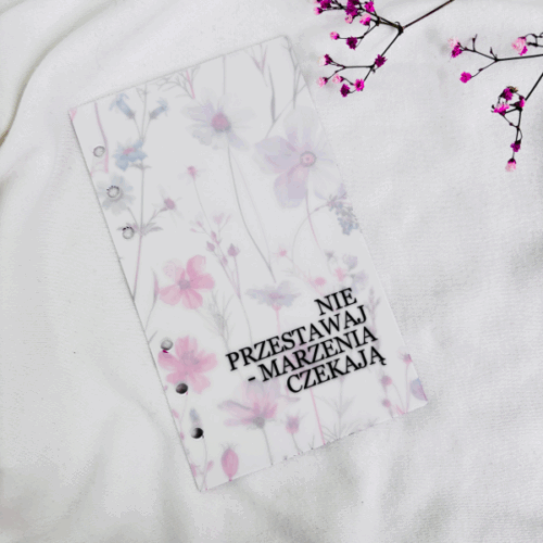 Okładka do segregatora A6 z napisem „PROGRES NIE PERFEKCJA” wykonana z półprzezroczystego tworzywa z kwiatowym wzorem.