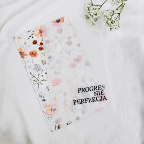 Okładka do segregatora z napisem „PROGRES NIE PERFEKCJA” i delikatnym wzorem kwiatów w ciepłych odcieniach na białym tle.