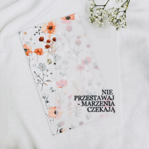 Okładka do segregatora z napisem „NIE PRZESTAWAJ – MARZENIA CZEKAJĄ” na tle kwiatowego wzoru w odcieniach pomarańczu i beżu.