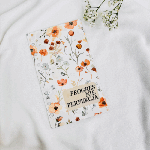 Okładka do segregatora z kwiatowym wzorem w kolorach beżu i pomarańczu, z napisem „PROGRES NIE PERFEKCJA” na beżowym tle.
